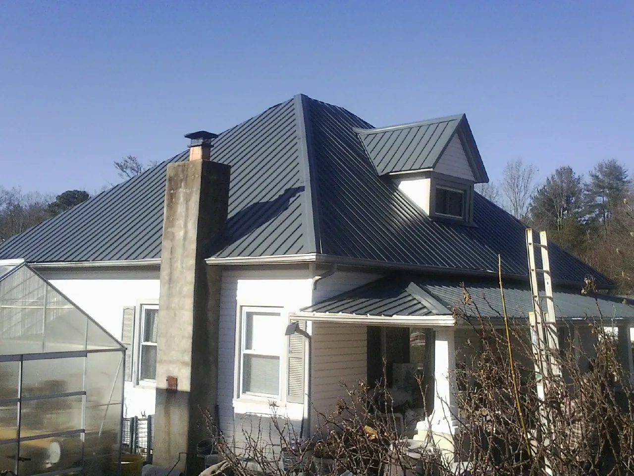 Dark blue standing seam metal roof on a white farmhouse with dormer — Slate & Tile Roof Repair by Roofing Brothers in Riceboro