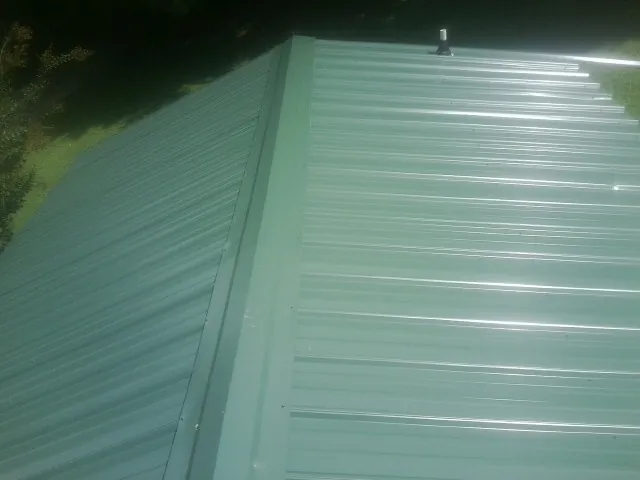 New green metal panels meeting at the ridge of a roof — Flat Roof Repair work by our crew in Riceboro
