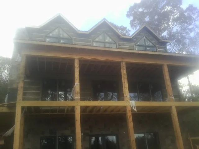 Dormers and porch framing on a large log home under construction — Roof Coating work by our crew in Riceboro