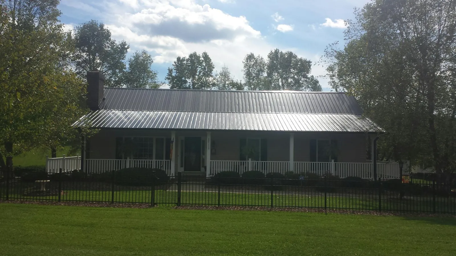 Gray metal roof on a brick ranch with a full width front porch — Gutter Guard Installation work by our crew in Riceboro