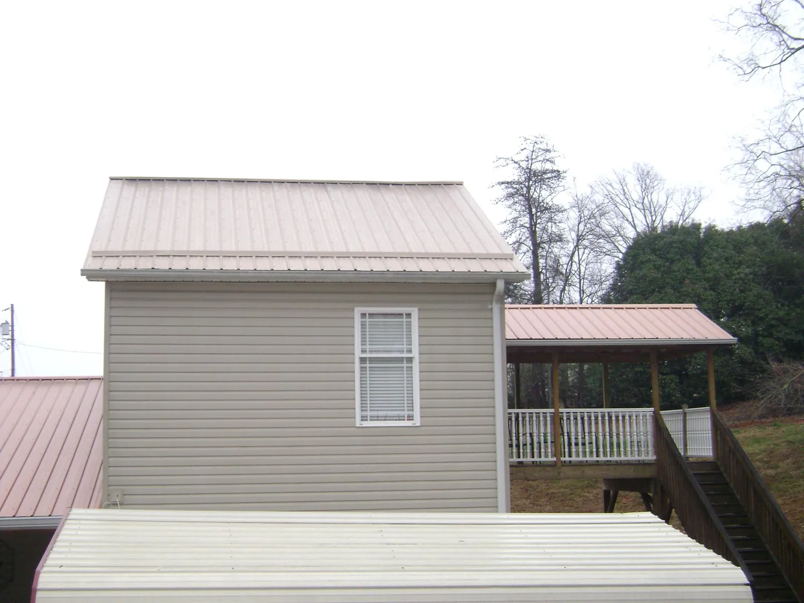 Tan metal roofs on a two story addition and attached porch, from a Roof Replacement job in Riceboro