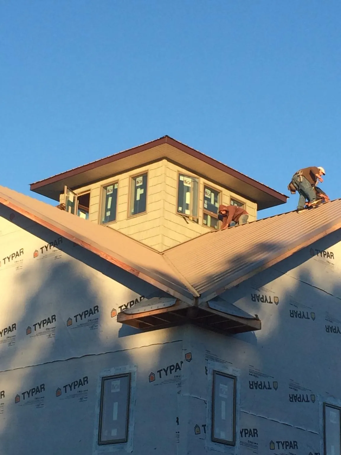 Roofers working around a rooftop cupola on a new metal roof at sunset — Roof Waterproofing in Riceboro by Roofing Brothers